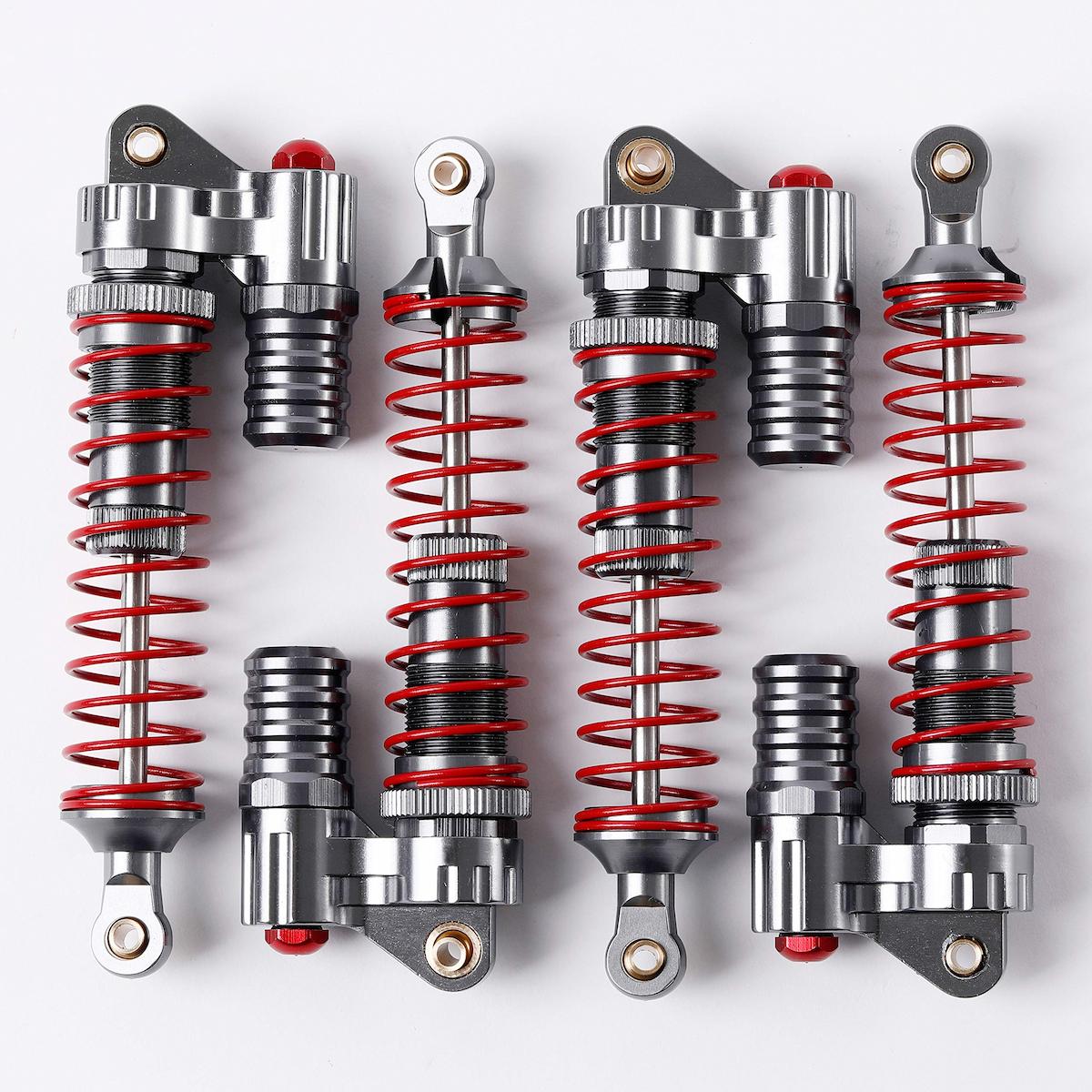 Four pairs of silver metal shock absorbers with bright red springs, arranged in two rows on a clean white background.